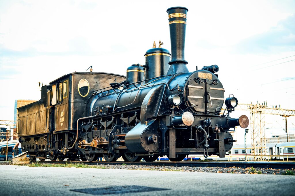 Classic steam locomotive captured in a vintage style at a train station during daytime.