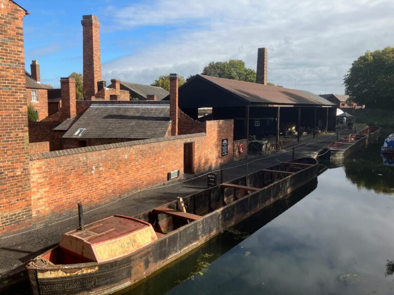 A picturesque view of canal barges and industrial buildings at the Black Country Living Museum in England.