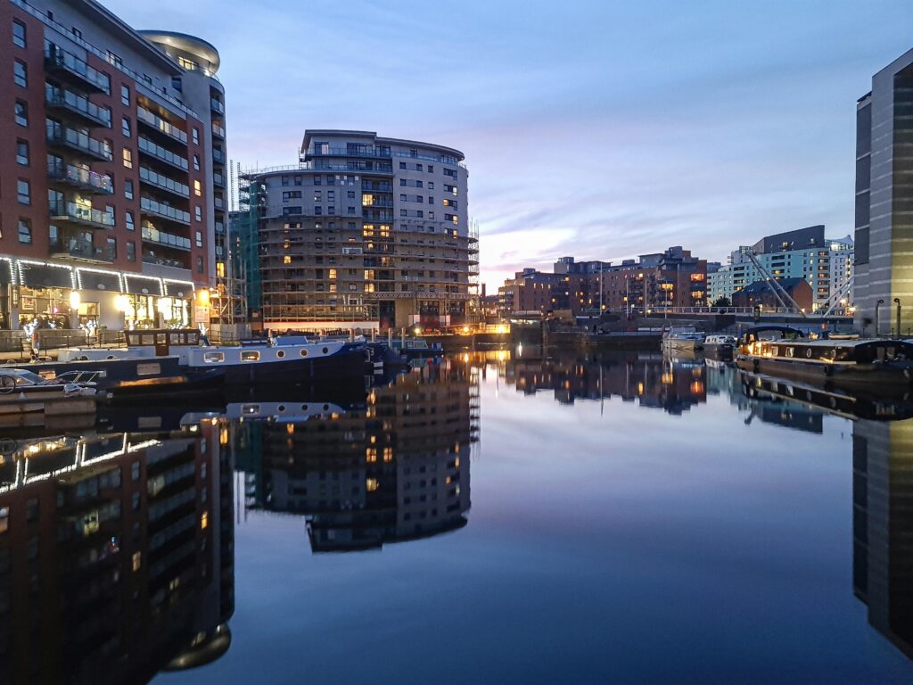 Evening view of Leeds Docks with reflections of modern apartments and calm waters.