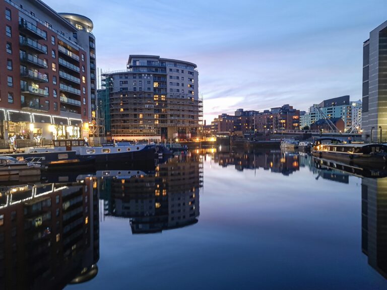 Evening view of Leeds Docks with reflections of modern apartments and calm waters.