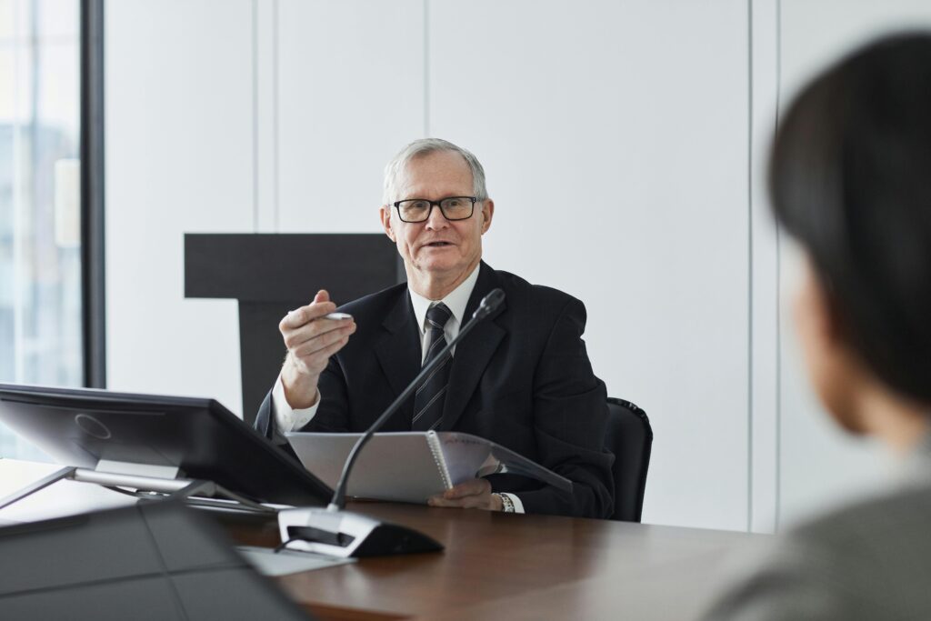 Senior businessman leading a professional discussion in a corporate meeting setting.