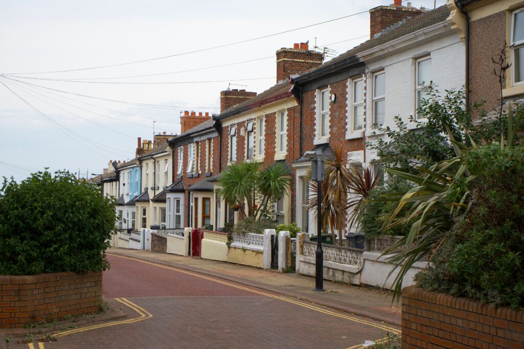 A picturesque view of colorful terraced houses lining a tree-lined alley in Liverpool, England.